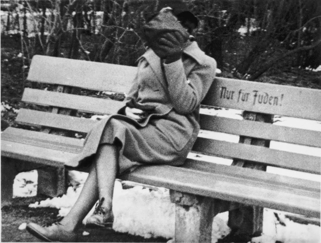A Jewish woman who is concealing her face sits on a park bench marked Only for Jews, Austria, 1938 (1)
