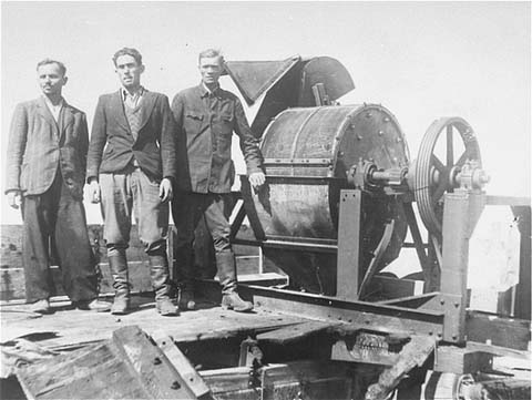 Members_of_a_Sonderkommando_1005_unit_pose_next_to_a_bone_crushing_machine_in_the_Janowska_concentration_camp